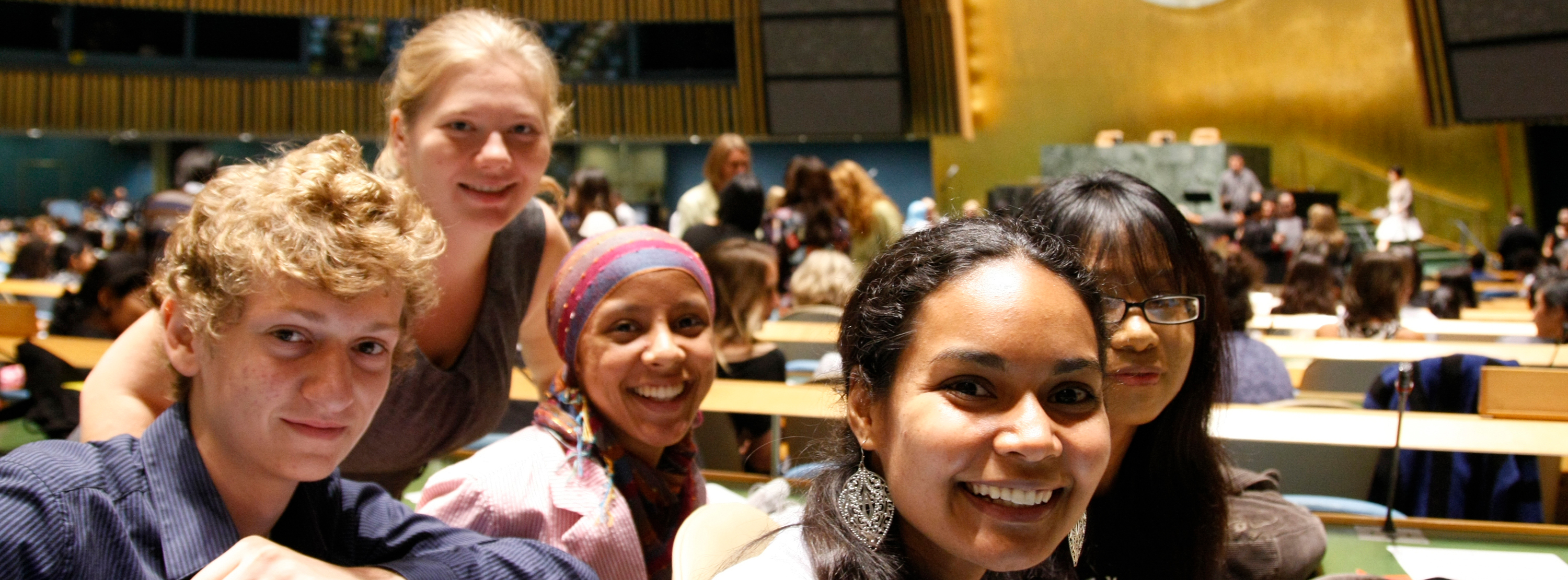 A group of young people smile from inside the General Assembly Hall.