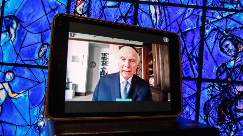 A tablet, with Rabbi Arthur Schneier on view, is leaning against Marc Chagall's colorful stained glass window at UNHQ.