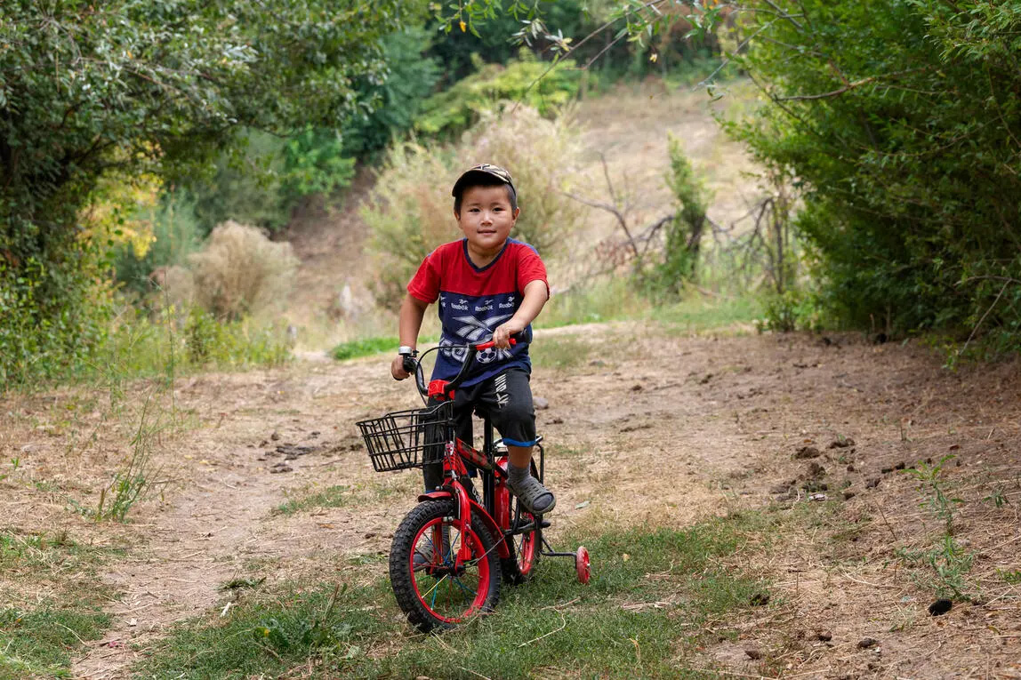 A boy on a bicycle with training wheels