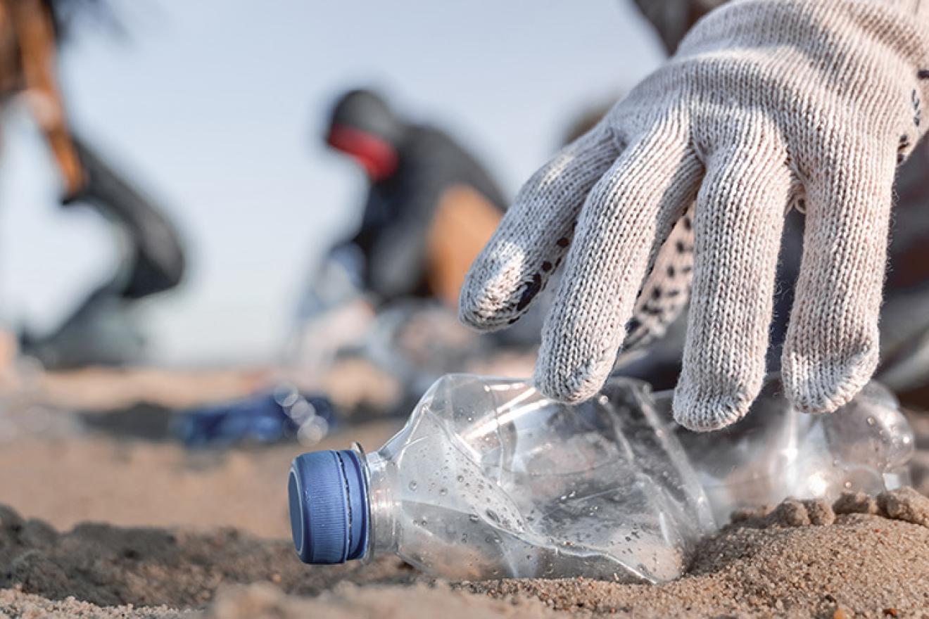 Close up of a hand taking a plastic bottle in the beach