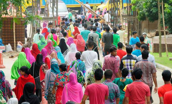 Бангладешские работники покидают швейную фабрику в конце рабочего дня.
