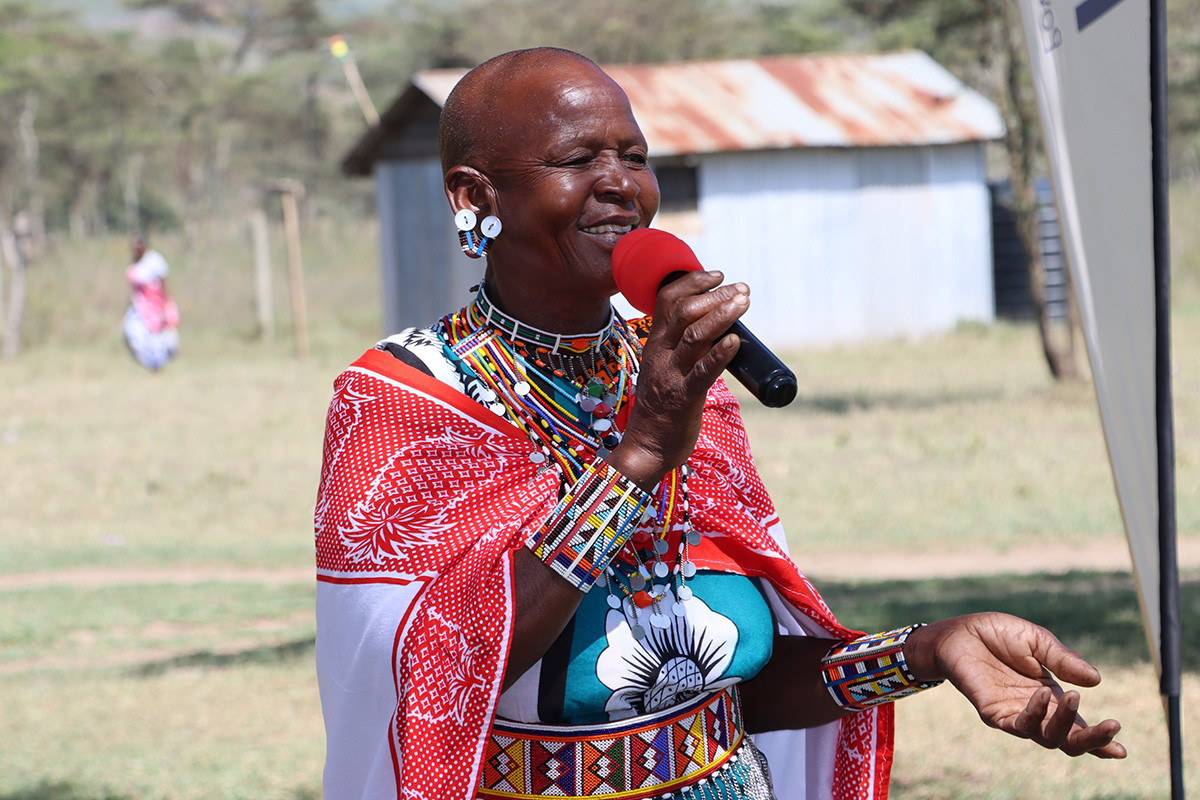 Mary Nkisonkoi is a Maasai woman and community facilitator, speaking into a microphone.