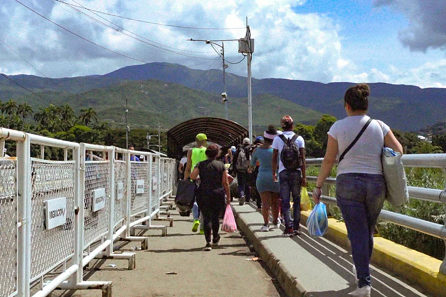 People cross a bridge on a border. 