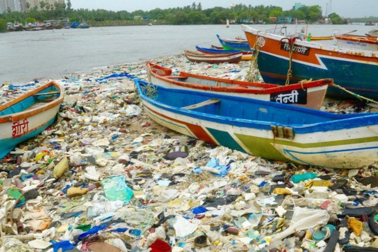 Des bateaux sur une plage recouverte de déchets plastiques