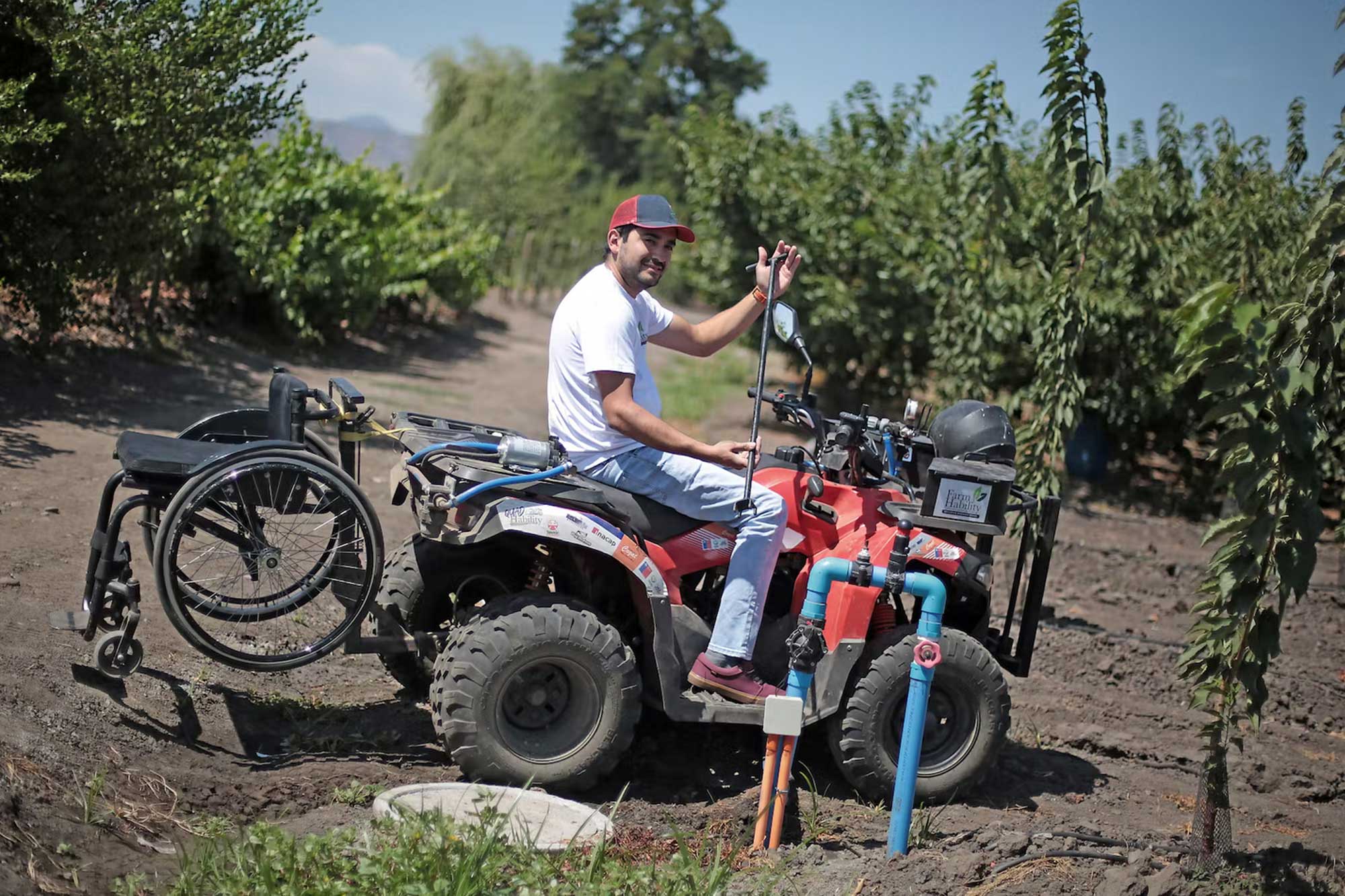 In a vast farmland, Alfredo sits in a tracktor with his wheelchair strapped on itsback.