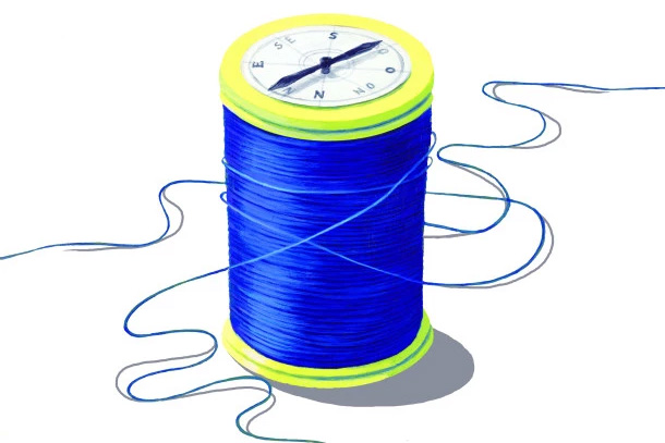 A spool of thread with a compass on top 