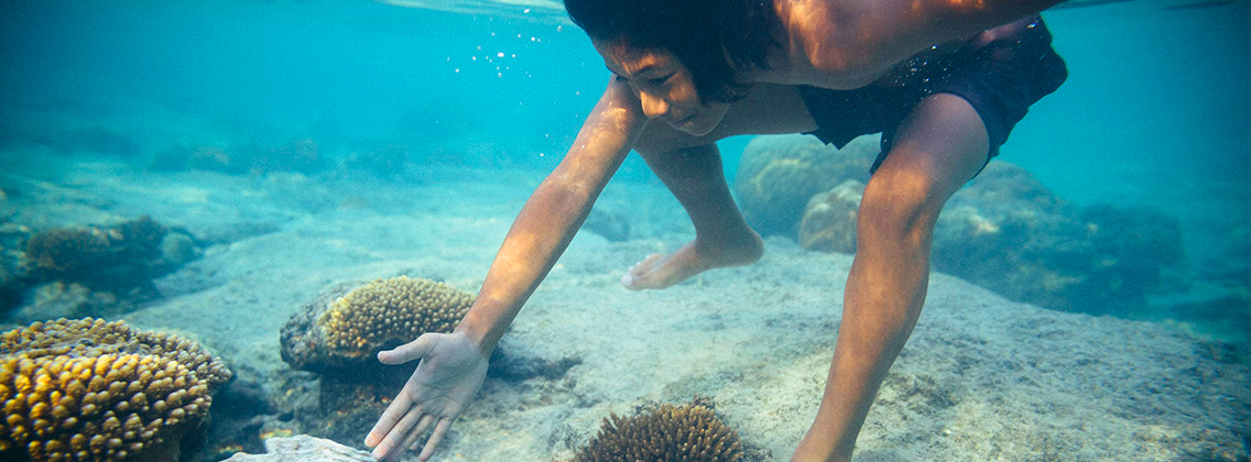 Kalio, 9, swims underwater near a shell of giant clam.
