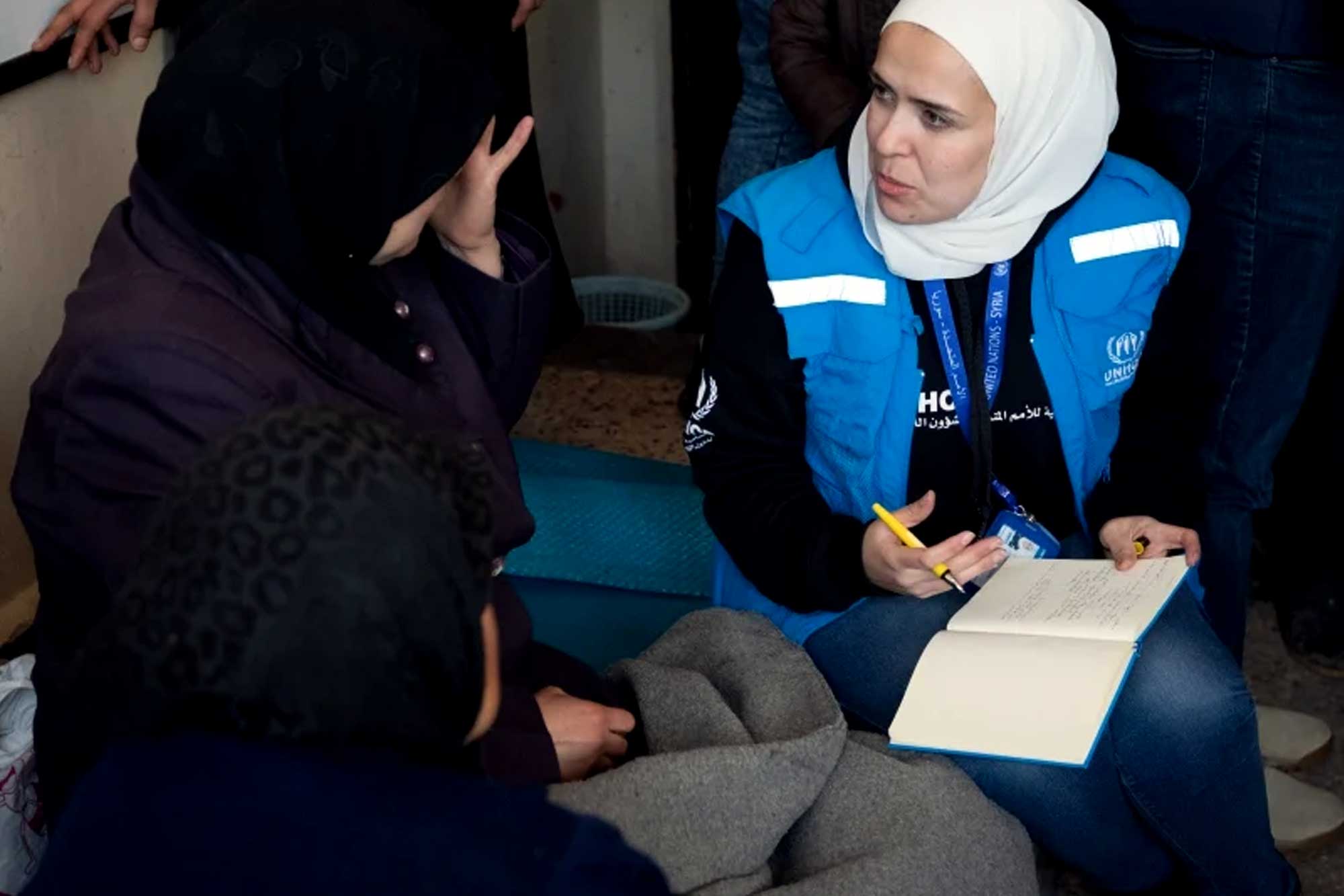 A woman wearing a UNHCR vest speaks to another woman in black