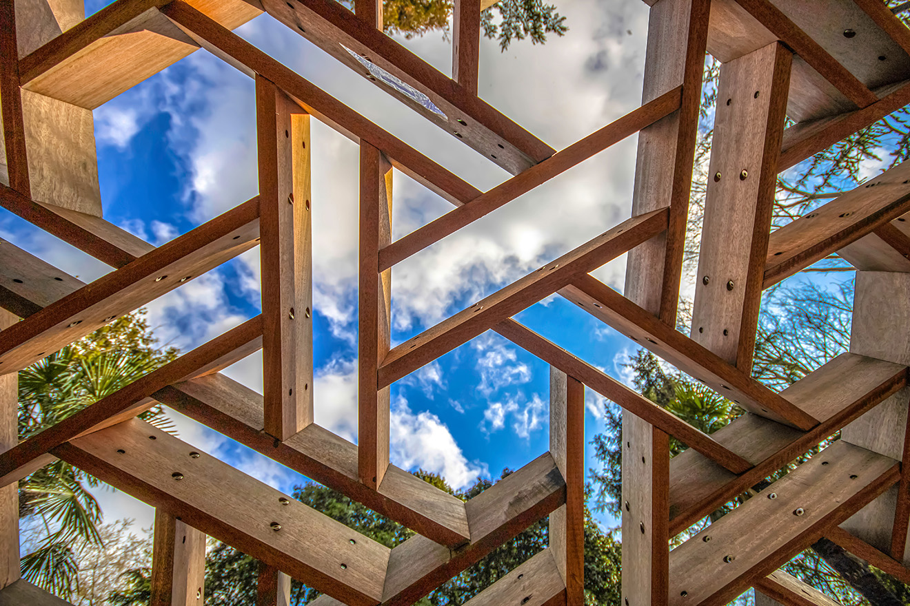 The blue cloudy sky seen through geometric wood frames
