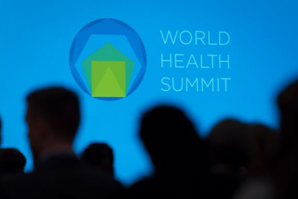 Silhouettes of people standing in front of sign that reads “World Health Summit”